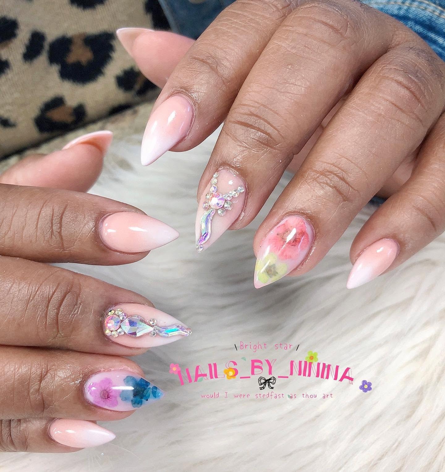Medium almond nails with glossy pink-to-white ombre, colorful watercolor accents, and accent nails decorated with iridescent rhinestone clusters.