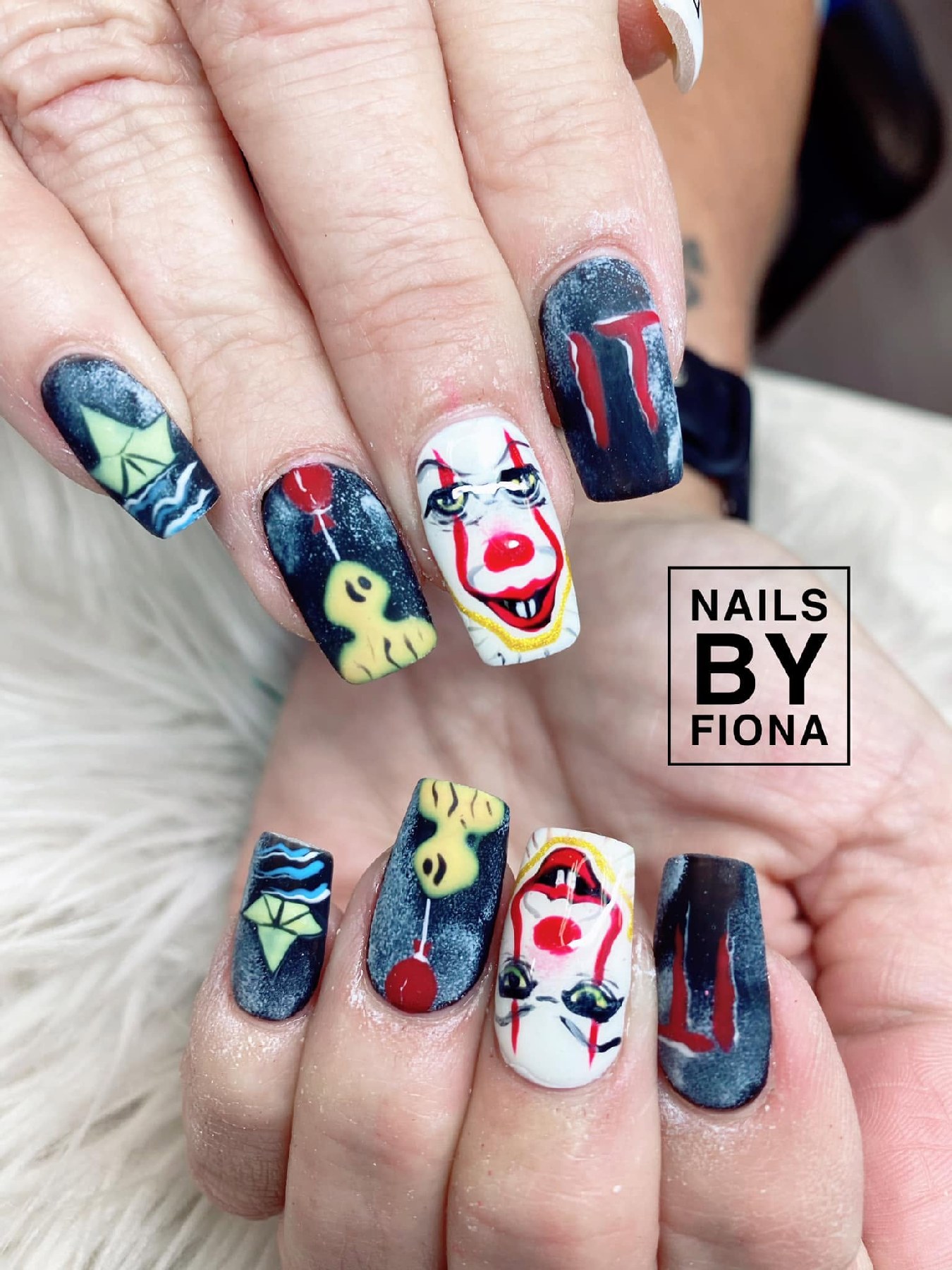 Long square nails with white horror-clown portraits, red balloons, yellow paper boats, dark navy backgrounds, and red lettering.