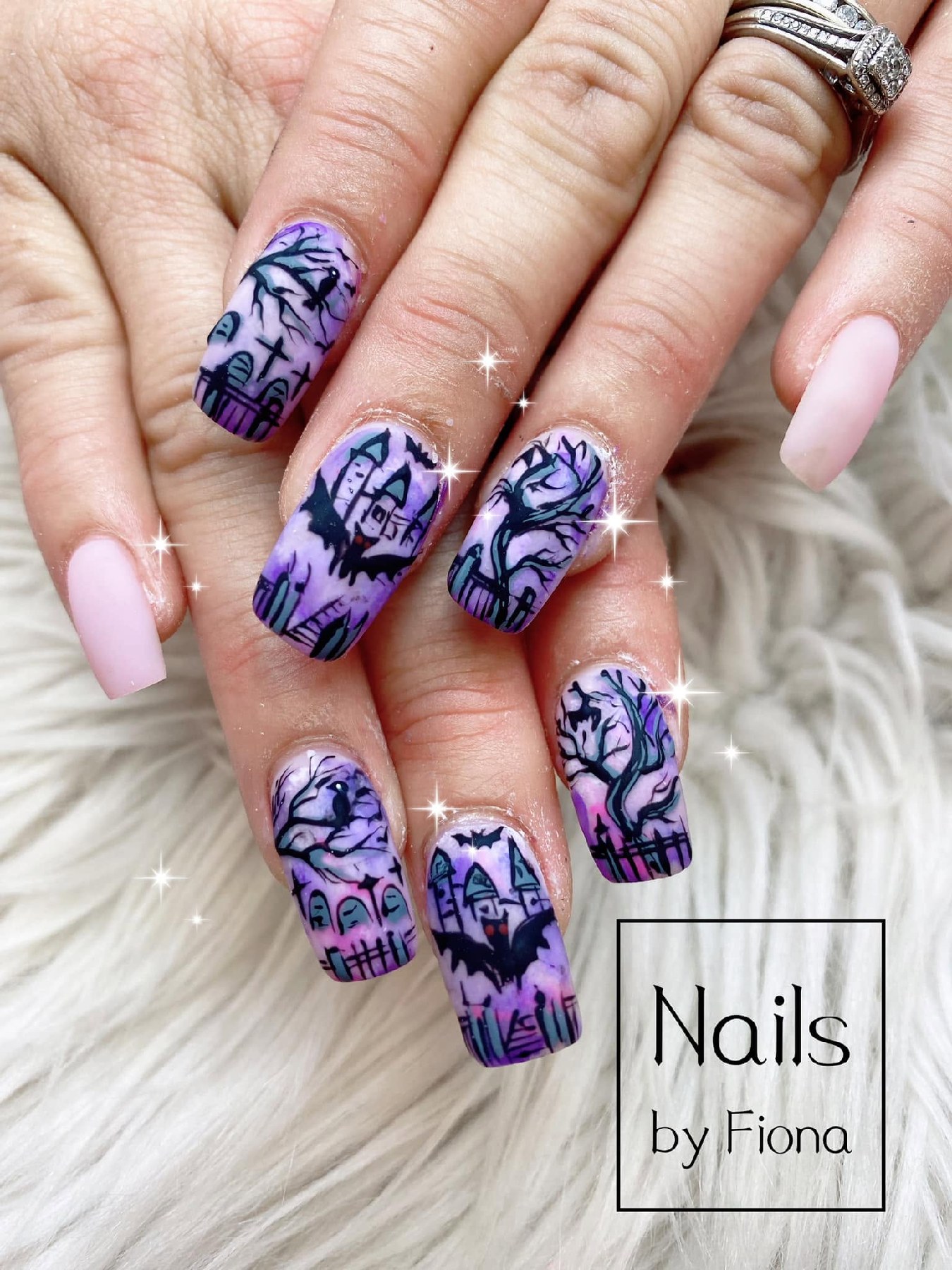 Long coffin nails with purple haunted landscapes, black castles, graveyards, bats, twisted trees, and pale-pink accent nails.