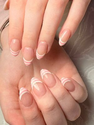 Medium almond nails with sheer pink bases and layered pink-and-white striped French tips in a glossy finish.