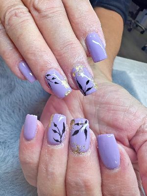 Medium square lavender nails with black leafy branch artwork and irregular gold foil accents on selected nails.