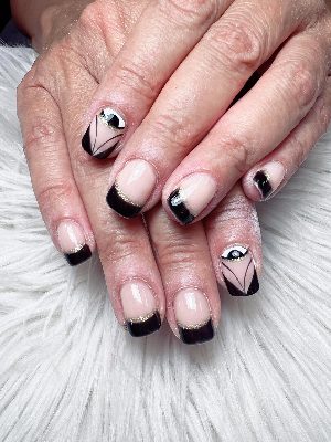 Short pink squoval nails have glossy black French tips, fine gold borders and graphic eye accent art.
