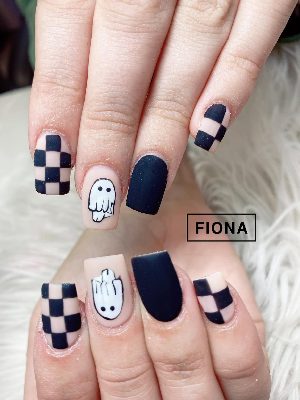 Matte square nails combine black solids, pink-and-black checkerboards and simple white ghost characters.
