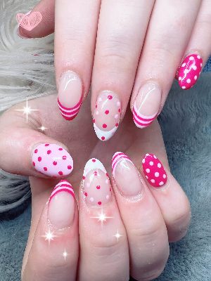 Medium almond nails with sheer pink bases, layered pink-and-white French tips, striped accents, and coordinating polka dots.