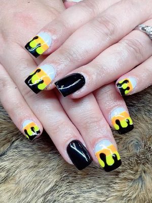 Short square nails with white, orange, and yellow color blocks topped by glossy black drip designs.