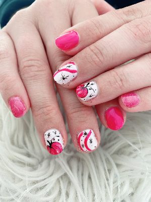 Short round hot-pink and white nails with pink pumpkins, black starbursts, curved stripes, and glitter accents.