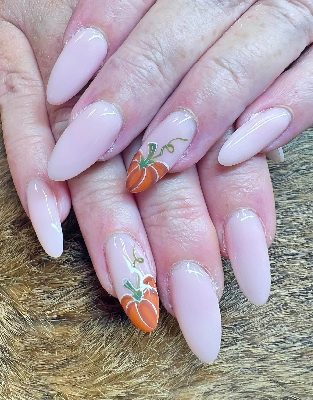 Long glossy almond nails in pale pink with orange pumpkin artwork, green stems, and curling vines on accent nails.