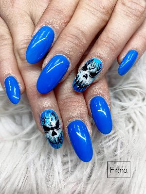 Long oval nails in vivid blue with two black-and-white skull face accents and dark tree-like details.