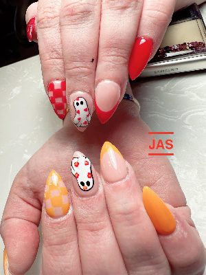 Long stiletto nails mixing red and orange tips, plaid, flowered ghosts, and small heart details.