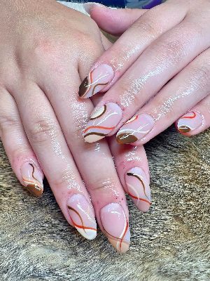Medium oval nude-pink nails with glossy brown and cream tip blocks plus thin orange, brown, and white curved lines.