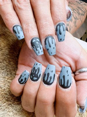 Long coffin nails with a matte gray base and black dripping patterns from alternating ends.