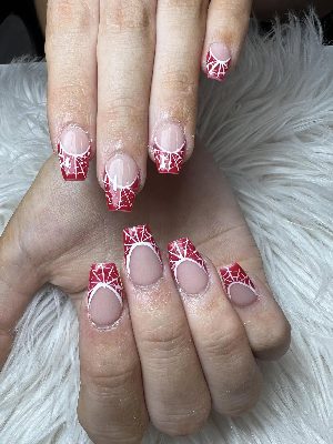 Long coffin nails with nude-pink centers, deep red French sections, and crisp white spiderweb line art.