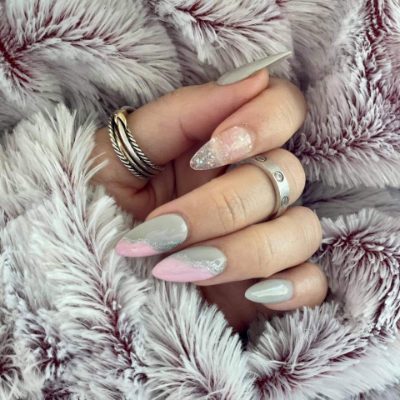 Long almond nails with gray and pink color blocking, curved silver glitter lines, and a sparkling accent nail.