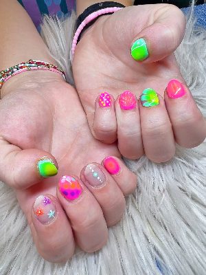 Short round nails with neon pink, green, teal, and orange designs featuring gradients, starfish, shells, dots, and swirls.