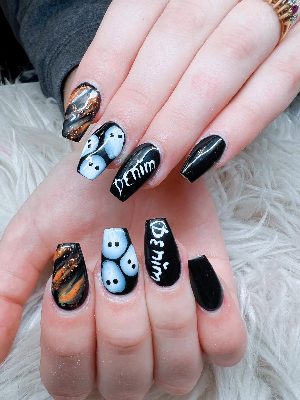 Long glossy black coffin nails with pale blue ghosts, white Destin lettering, and orange-copper marbled glitter accents.
