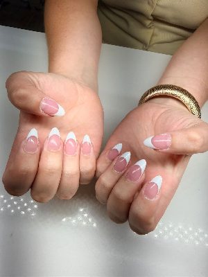 Medium almond nails with a sheer pink base and crisp curved white French tips on both hands.
