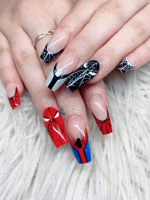 Long coffin nails with red and black spiderweb art, white spiders, mask-like eye details, and a red-blue accent.