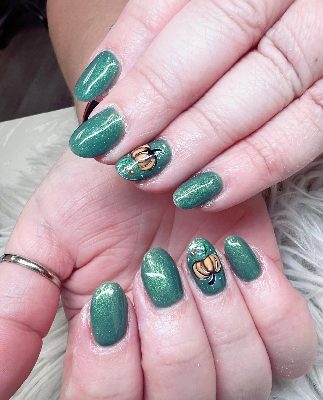 Medium oval green shimmer nails with orange pumpkin and leaf artwork on two accent nails.
