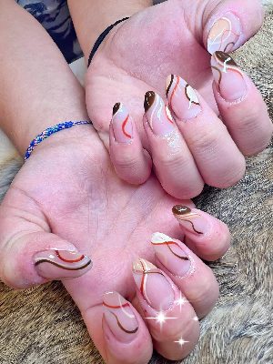 Glossy nude-pink oval nails with brown and cream tip sections and slim orange, white, and brown wavy lines.