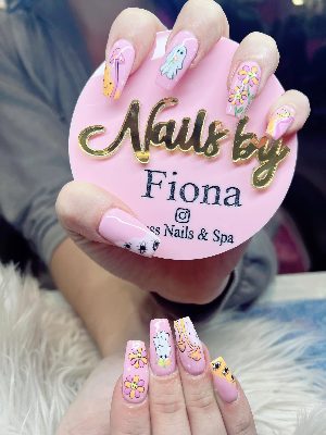 Long pink coffin nails with ghosts, smiling flowers, mushrooms, a crescent moon, eye motifs, stars, and pastel waves.