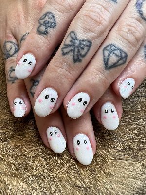 Medium oval white shimmer nails with simple black ghost eyes and small pink cheeks on every nail.