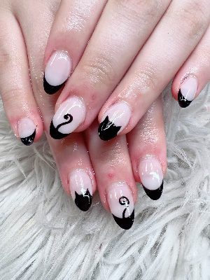 Medium oval nails with pale pink bases, glossy black French tips, and black cat silhouettes integrated into the tips.