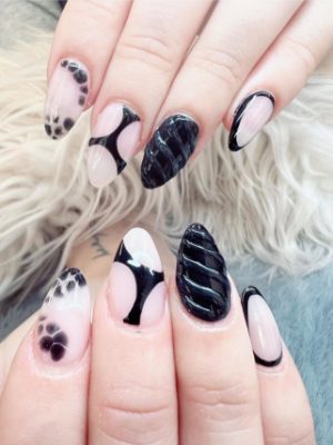 Almond nails with black abstract curves, spotted accents, and raised glossy black texture over pale nude nails.