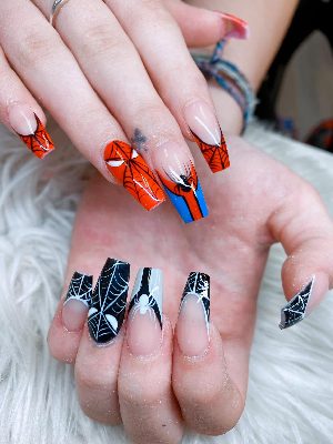 Long square nails with orange superhero-mask and web art on one hand and black-and-white spiderweb French designs on the other.