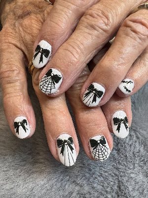 Medium oval white nails with black bows, spiderwebs, bats and fine radiating line details.