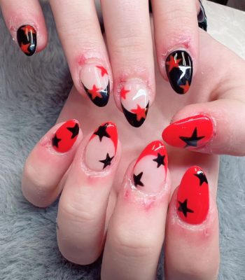 Almond nails with red, black, and nude color blocking plus bold star shapes.