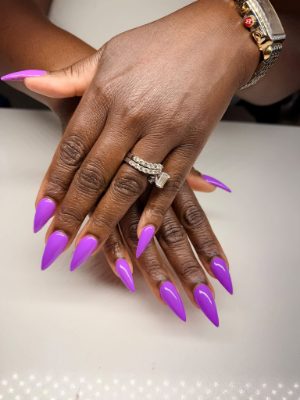 Long stiletto nails painted a uniform glossy vivid purple on both hands.
