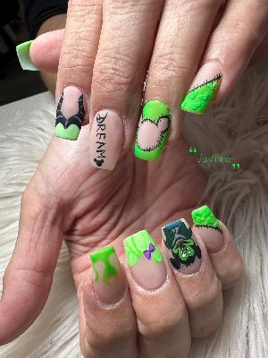 Long coffin nails with neon green drips, stitched patches, dimensional texture, and cartoon-inspired character art.