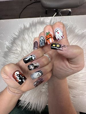 Long square nails covered in detailed Halloween art including ghosts, a pumpkin, skeleton, black cat, witch, and webs.