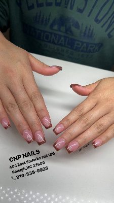Medium square nails with a glossy pink base and slim brown French tips; salon contact text appears below the hands.